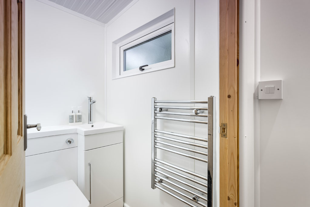 Interior of a TGO1 bathroom with a heated towel rail, a tap and liquid soap