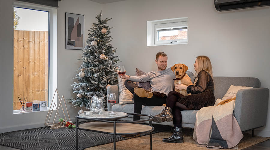 family sat on sofa with dog in Christmas environment