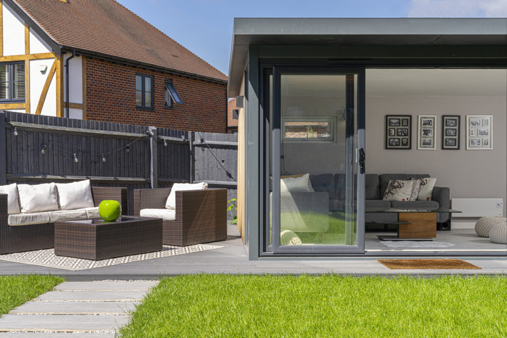 Exterior of a garden room on a patio with garden furniture to the left
